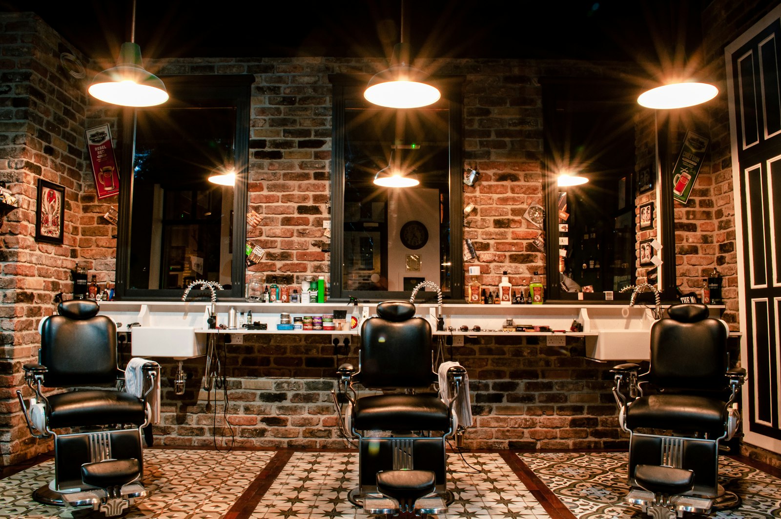 Three barber chairs against an exposed brick wall