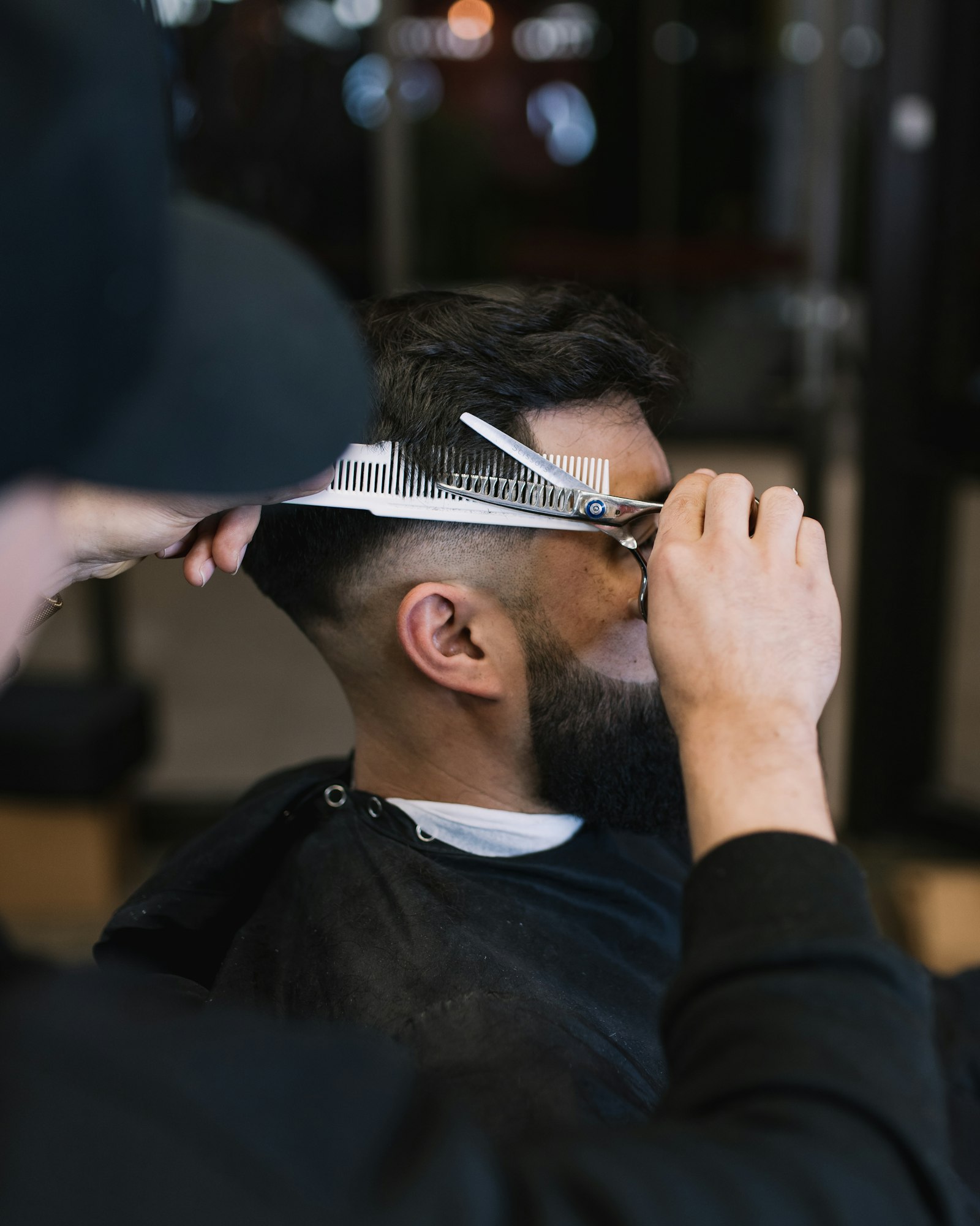 Barber working a fade with comb and shears